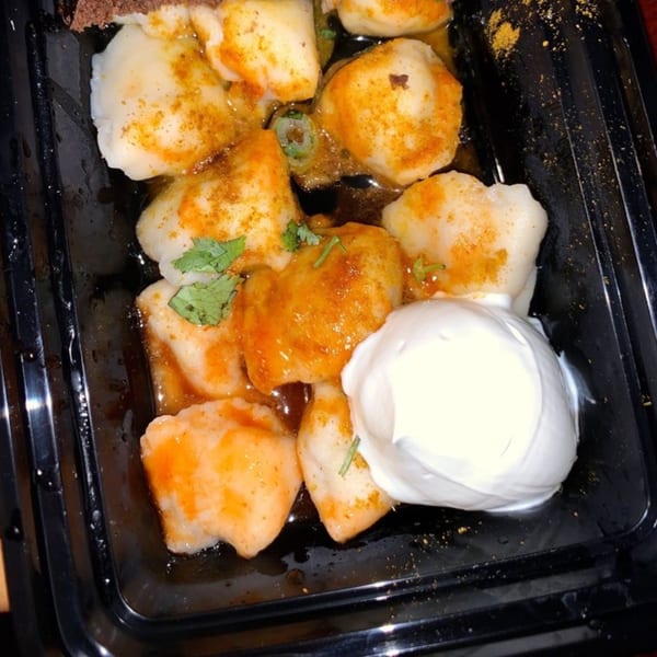 Pel Meni Dumpling Tzar dumplings with sauce, spices, cilantro, and a dollop of sour cream.