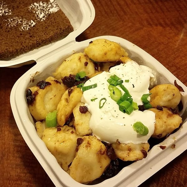 Pel Meni Dumpling Tzar dumplings with sour cream and green onions, next to a piece of cake.