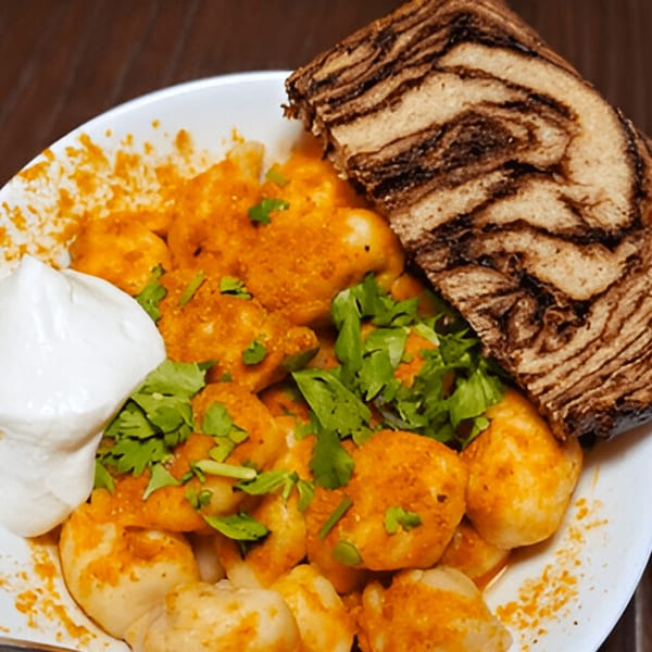 Pel Meni Dumpling Tzar's dumplings with sour cream, cilantro, and a slice of marbled bread.
